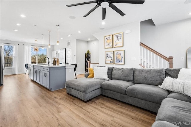 living room with sink, light hardwood / wood-style flooring, and ceiling fan