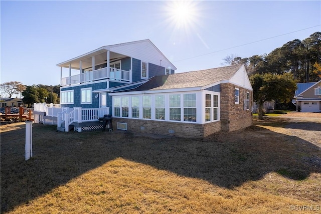 exterior space featuring a sunroom, a balcony, a yard, and a wooden deck