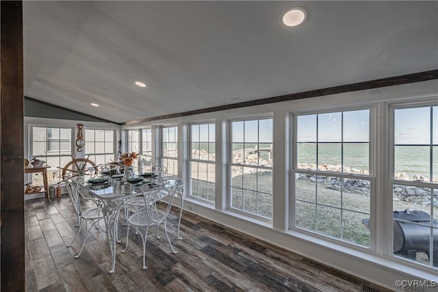 unfurnished dining area with dark hardwood / wood-style flooring, a water view, lofted ceiling, and a wealth of natural light