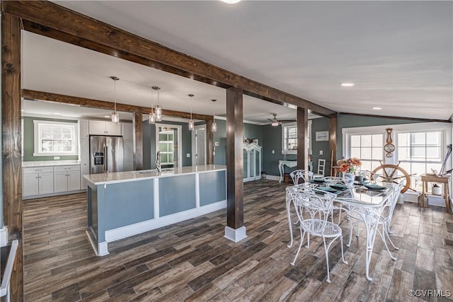 kitchen featuring stainless steel fridge, dark hardwood / wood-style flooring, decorative light fixtures, and vaulted ceiling with beams