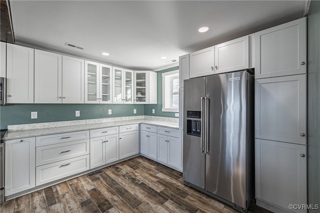 kitchen with white cabinetry, light stone countertops, dark hardwood / wood-style floors, and appliances with stainless steel finishes