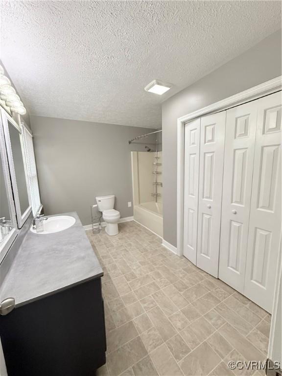 full bathroom with vanity, toilet,  shower combination, and a textured ceiling