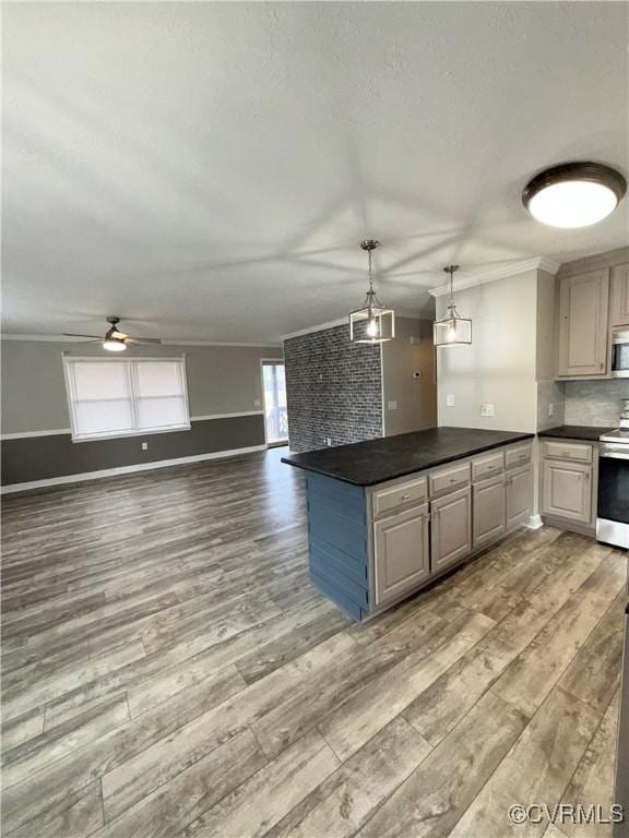 kitchen featuring pendant lighting, hardwood / wood-style flooring, crown molding, appliances with stainless steel finishes, and tasteful backsplash