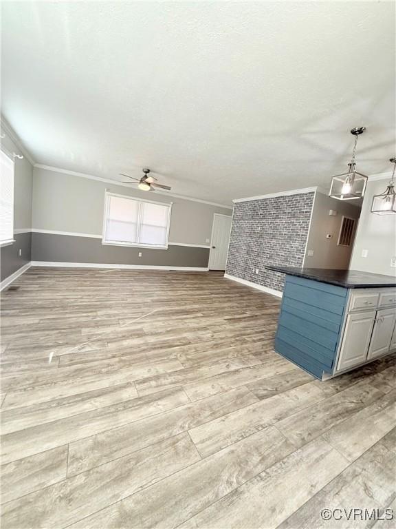 unfurnished living room featuring crown molding, ceiling fan, and light hardwood / wood-style floors