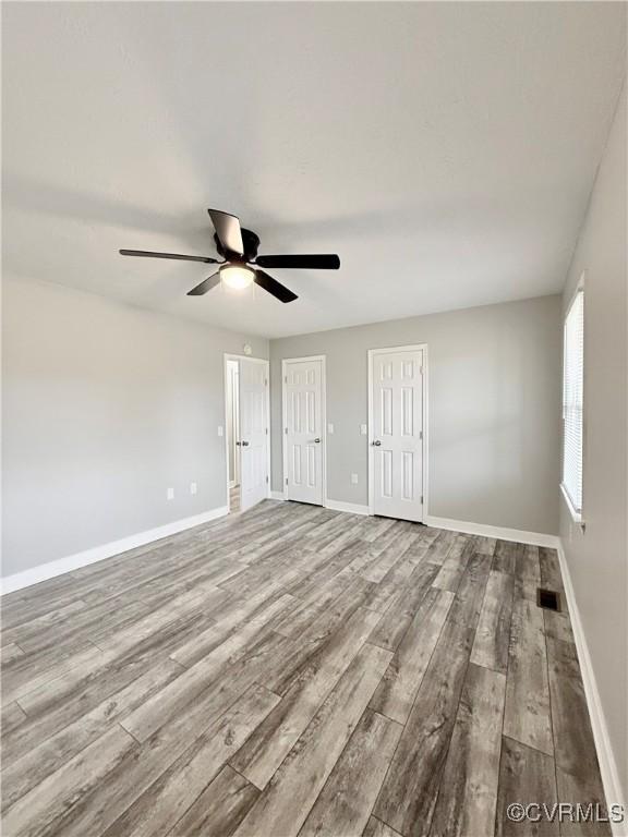 empty room with ceiling fan and light hardwood / wood-style floors