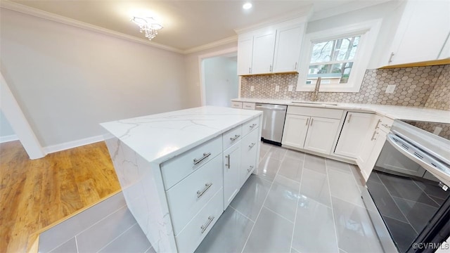 kitchen featuring decorative backsplash, appliances with stainless steel finishes, sink, white cabinets, and a center island