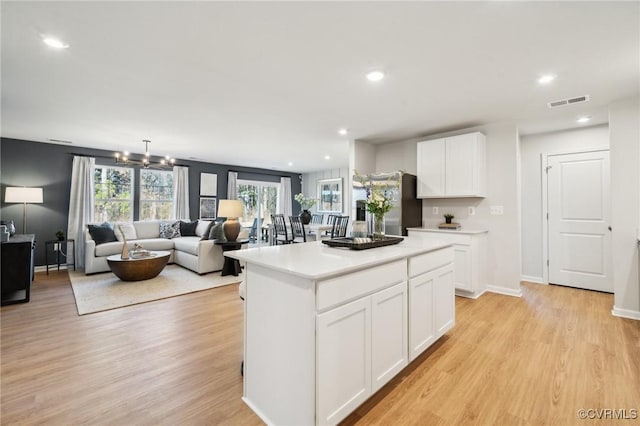 kitchen featuring a center island, a chandelier, white cabinets, and light hardwood / wood-style floors