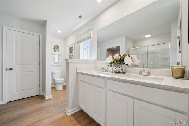 bathroom featuring vanity, hardwood / wood-style flooring, toilet, and walk in shower