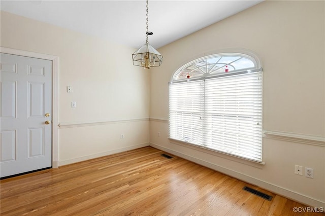 unfurnished dining area featuring a notable chandelier and light hardwood / wood-style flooring