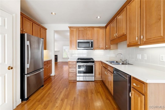 kitchen with backsplash, stainless steel appliances, light hardwood / wood-style flooring, and sink