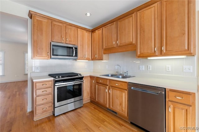 kitchen with backsplash, sink, appliances with stainless steel finishes, and light hardwood / wood-style flooring