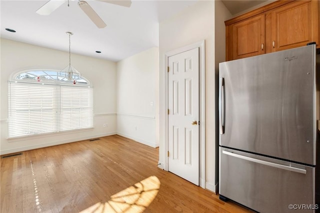 kitchen with stainless steel refrigerator, ceiling fan, hanging light fixtures, and light hardwood / wood-style floors