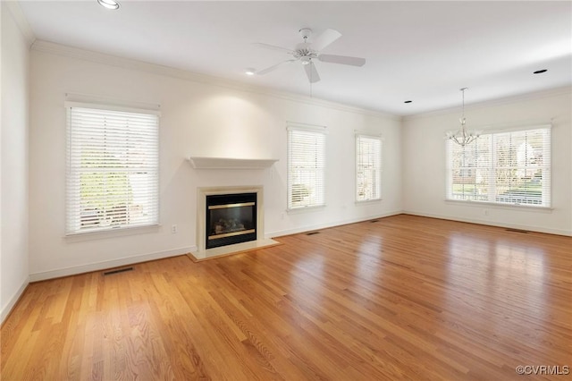 unfurnished living room with ceiling fan with notable chandelier, light wood-type flooring, and ornamental molding