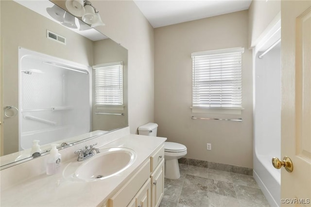 bathroom with a shower, a wealth of natural light, vanity, and toilet