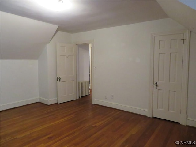 additional living space with lofted ceiling, radiator heating unit, and dark hardwood / wood-style floors