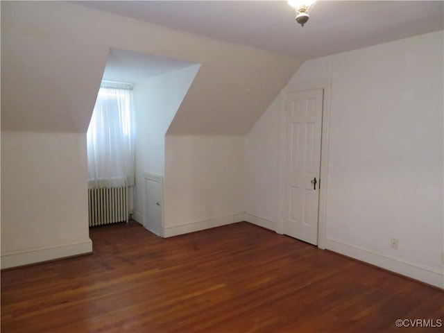 additional living space with radiator heating unit, dark hardwood / wood-style floors, and lofted ceiling