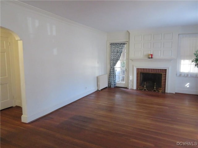 unfurnished living room featuring dark hardwood / wood-style floors, radiator heating unit, and a brick fireplace