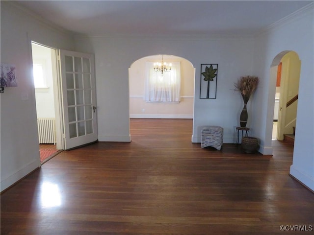 unfurnished room with radiator heating unit, dark hardwood / wood-style floors, an inviting chandelier, and ornamental molding