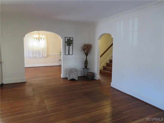 spare room featuring ornamental molding, dark wood-type flooring, and a chandelier