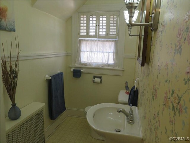 bathroom featuring radiator heating unit, sink, vaulted ceiling, and toilet