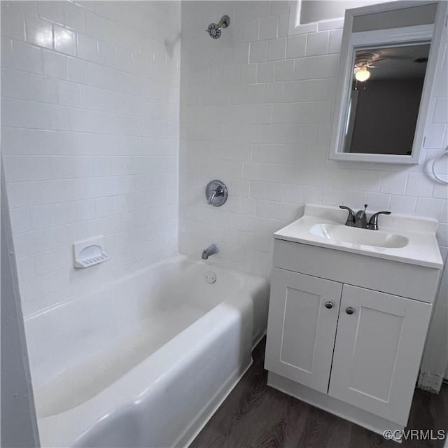 bathroom featuring vanity, hardwood / wood-style floors, tiled shower / bath combo, and tile walls