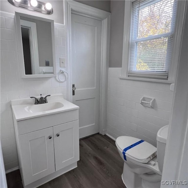 bathroom with vanity, hardwood / wood-style flooring, toilet, and tile walls