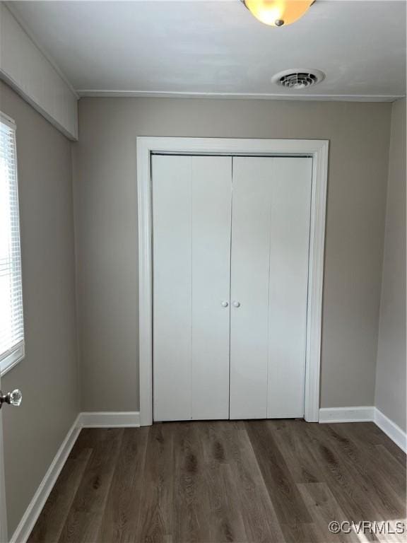 unfurnished bedroom featuring a closet and dark hardwood / wood-style floors