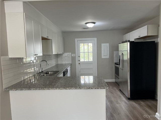 kitchen with white cabinetry, sink, stainless steel appliances, kitchen peninsula, and light wood-type flooring