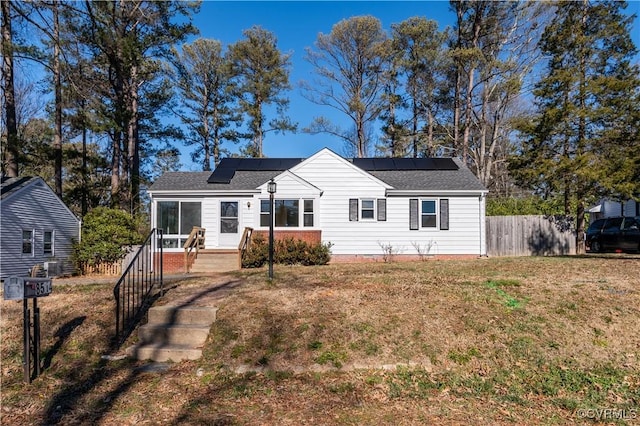 view of front of home with a front yard and solar panels