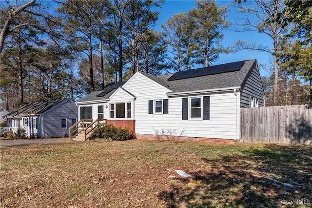 view of front of home with solar panels and a front yard