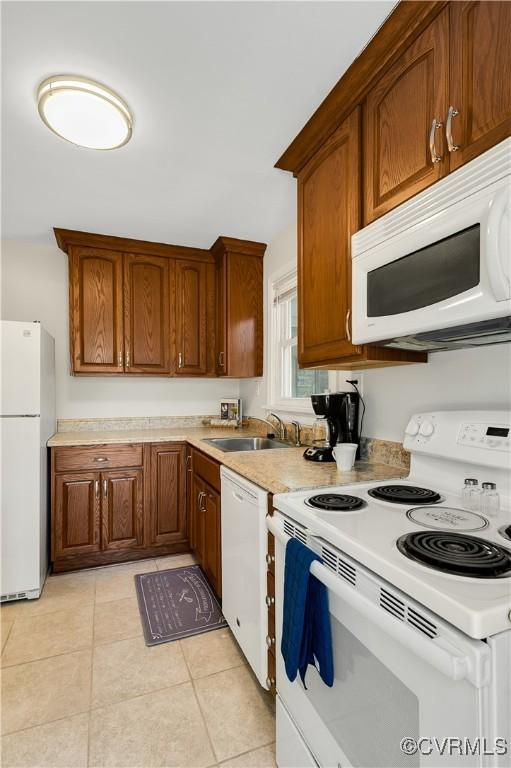 kitchen with white appliances, light tile patterned flooring, and sink