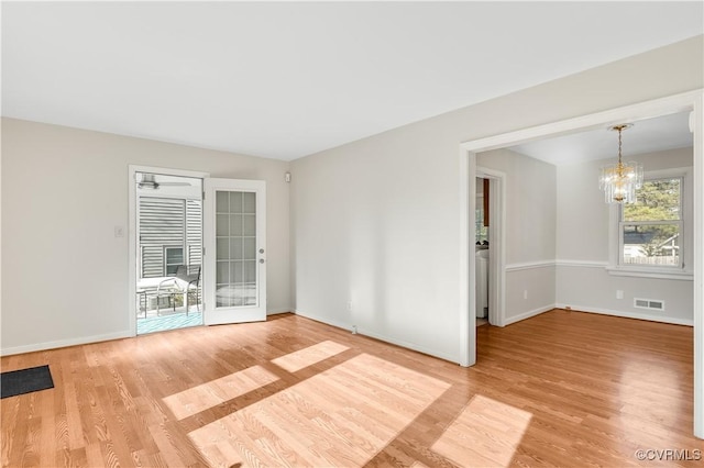 unfurnished room featuring french doors, an inviting chandelier, and light hardwood / wood-style floors