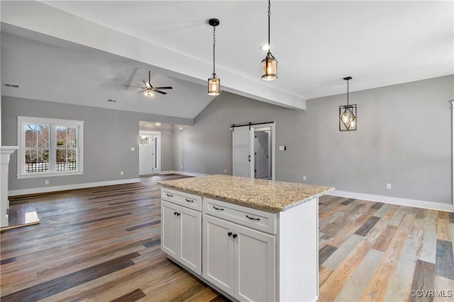 kitchen featuring ceiling fan, a barn door, vaulted ceiling with beams, hanging light fixtures, and white cabinets