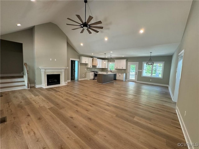 unfurnished living room with ceiling fan, light hardwood / wood-style flooring, and high vaulted ceiling