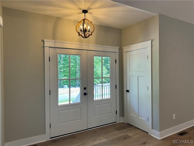 doorway to outside featuring hardwood / wood-style flooring, french doors, and a notable chandelier