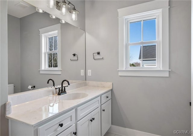 bathroom featuring toilet, plenty of natural light, and vanity