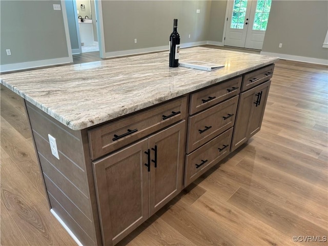 kitchen with light hardwood / wood-style floors, light stone counters, and a center island