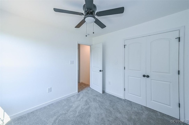 unfurnished bedroom with a closet, light colored carpet, and ceiling fan