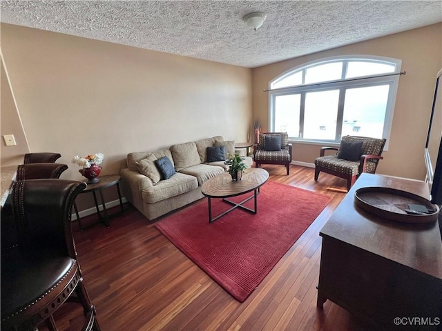 living room with a textured ceiling and dark hardwood / wood-style floors