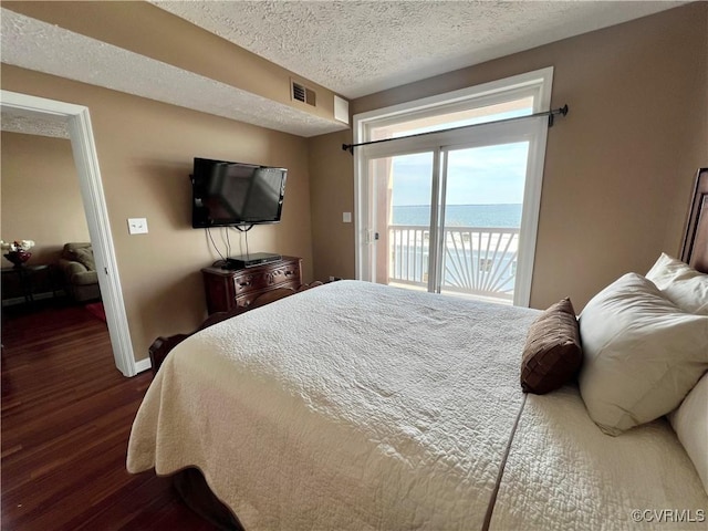 bedroom with a textured ceiling, access to exterior, and dark hardwood / wood-style floors