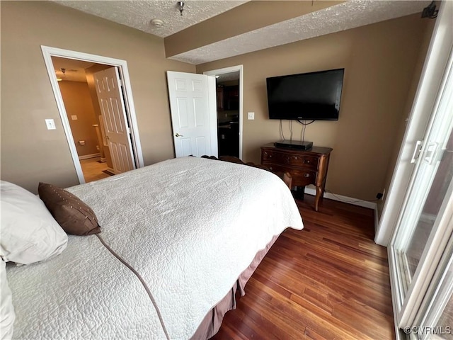 bedroom with connected bathroom, dark hardwood / wood-style floors, and a textured ceiling