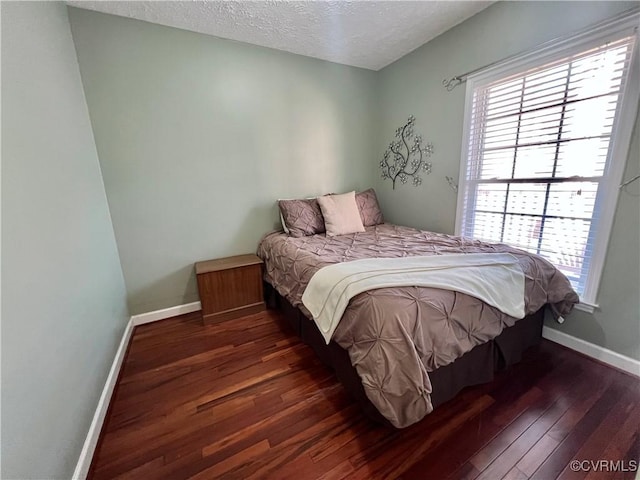 bedroom featuring dark hardwood / wood-style flooring, a textured ceiling, and multiple windows