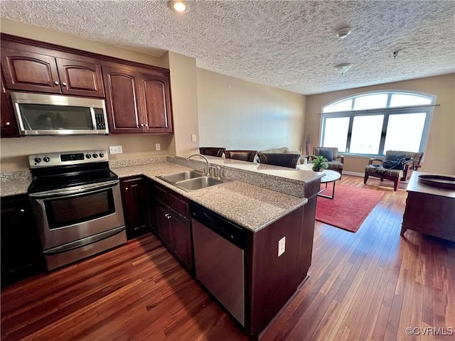 kitchen with kitchen peninsula, appliances with stainless steel finishes, dark hardwood / wood-style flooring, and sink