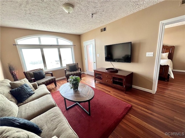 living room with a textured ceiling and dark hardwood / wood-style floors