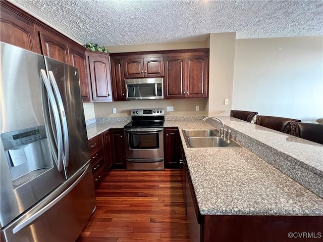 kitchen featuring sink, a textured ceiling, dark hardwood / wood-style flooring, kitchen peninsula, and stainless steel appliances