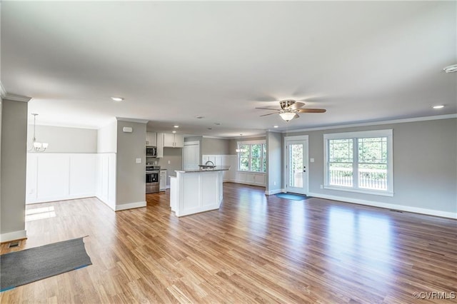 unfurnished living room featuring ceiling fan with notable chandelier, light hardwood / wood-style floors, and ornamental molding