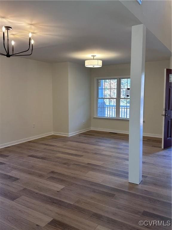 spare room with dark hardwood / wood-style flooring and a notable chandelier