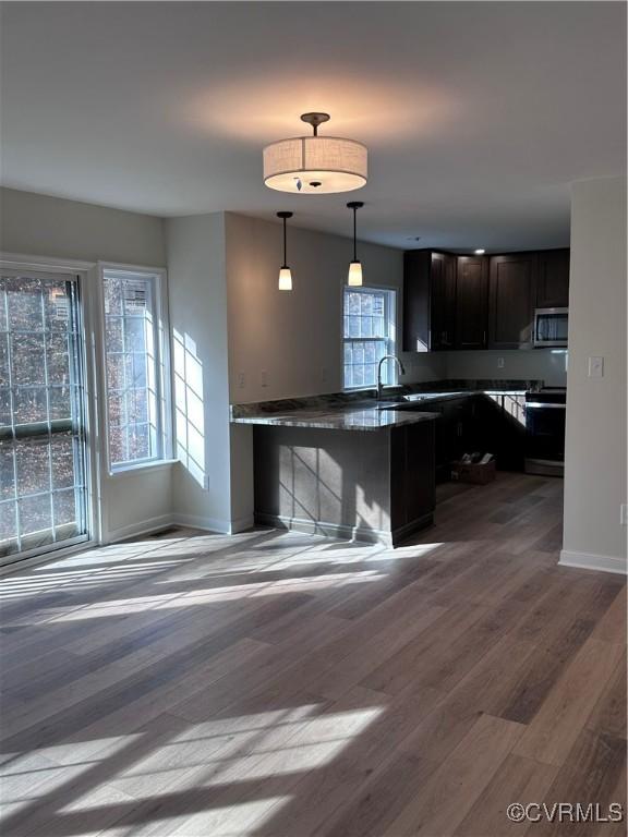 kitchen with dark brown cabinets, electric stove, decorative light fixtures, dark hardwood / wood-style floors, and a breakfast bar area