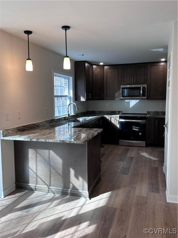 kitchen with kitchen peninsula, light stone countertops, stainless steel appliances, decorative light fixtures, and hardwood / wood-style floors