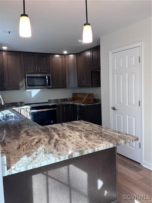 kitchen with hardwood / wood-style floors, black / electric stove, dark brown cabinets, and hanging light fixtures